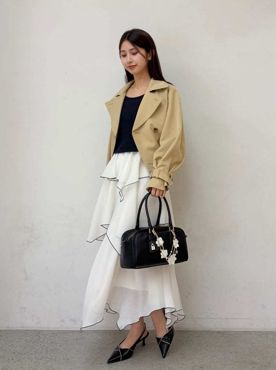 ベージュ系のトレンチコート、ブルー系のワンピース、ブラック系のパンプスを着用したレディースの冬コーディネートの2枚目の写真