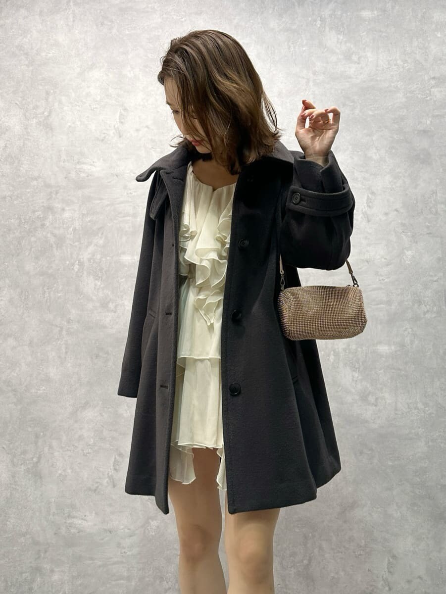 グレー系のステンカラーコート、ホワイト系のワンピースを着用したレディースの秋コーディネートの5枚目の写真