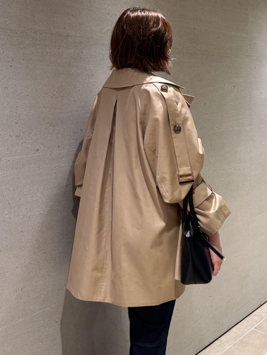 ブルー系のデニムパンツ、ベージュ系のトレンチコート、ブルー系のキャミソールを着用したレディースの秋コーディネートの7枚目の写真