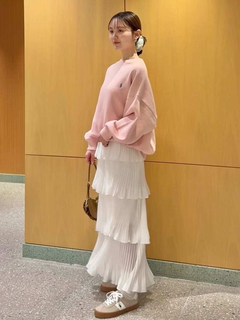 ホワイト系のスカート、ピンク系のスウェット、ブラウン系のハンドバッグを着用したレディースの春コーディネートの3枚目の写真