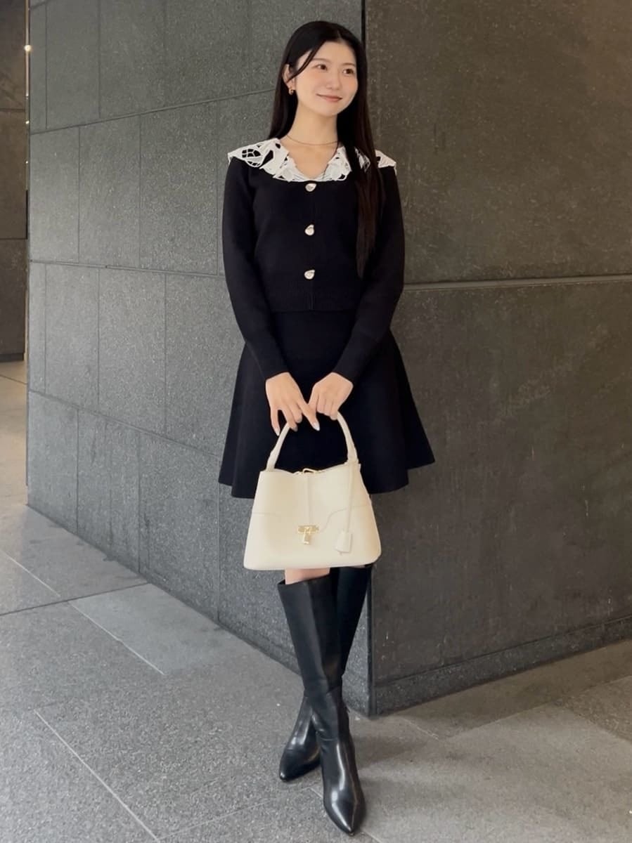 ブラック系のブーツ、ブラック系のワンピース、ホワイト系のハンドバッグを着用したレディースの冬コーディネートの2枚目の写真