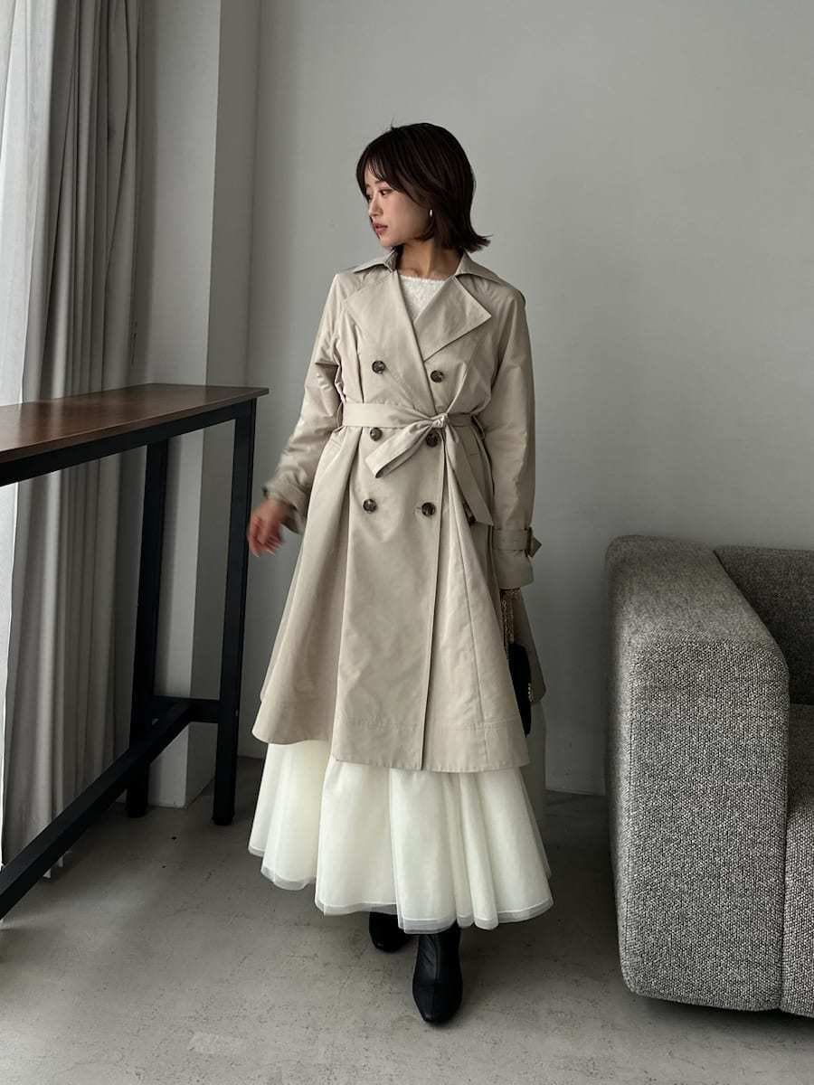 ベージュ系のトレンチコート、ベージュ系のワンピース、ブラック系のショルダーバッグを着用したレディースの春コーディネートの3枚目の写真