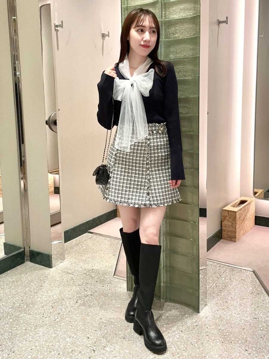 ブルー系のニット/セーター、ホワイト系のスカート、ブラック系のショルダーバッグを着用したレディースの秋コーディネートの2枚目の写真