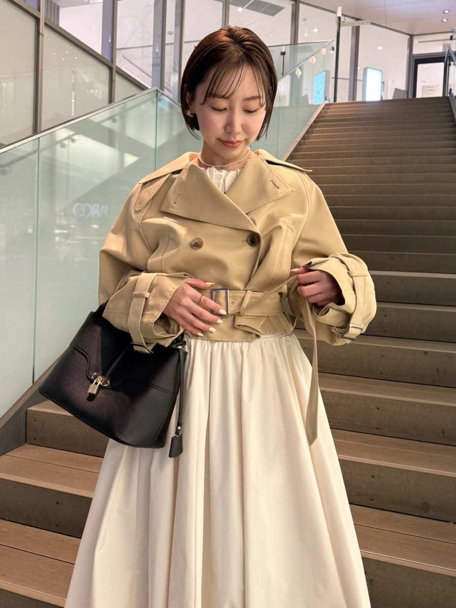 ベージュ系のトレンチコート、ホワイト系のスカート、その他のニット/セーターを着用したレディースの冬コーディネートの2枚目の写真