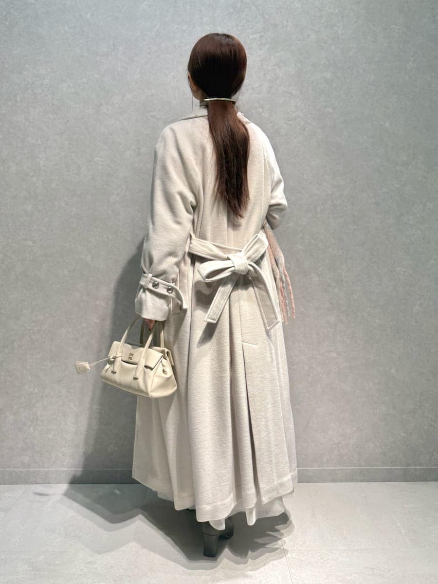 ピンク系のニット/セーター、ホワイト系のチェスターコート、ホワイト系のスカートを着用したレディースの冬コーディネートの2枚目の写真