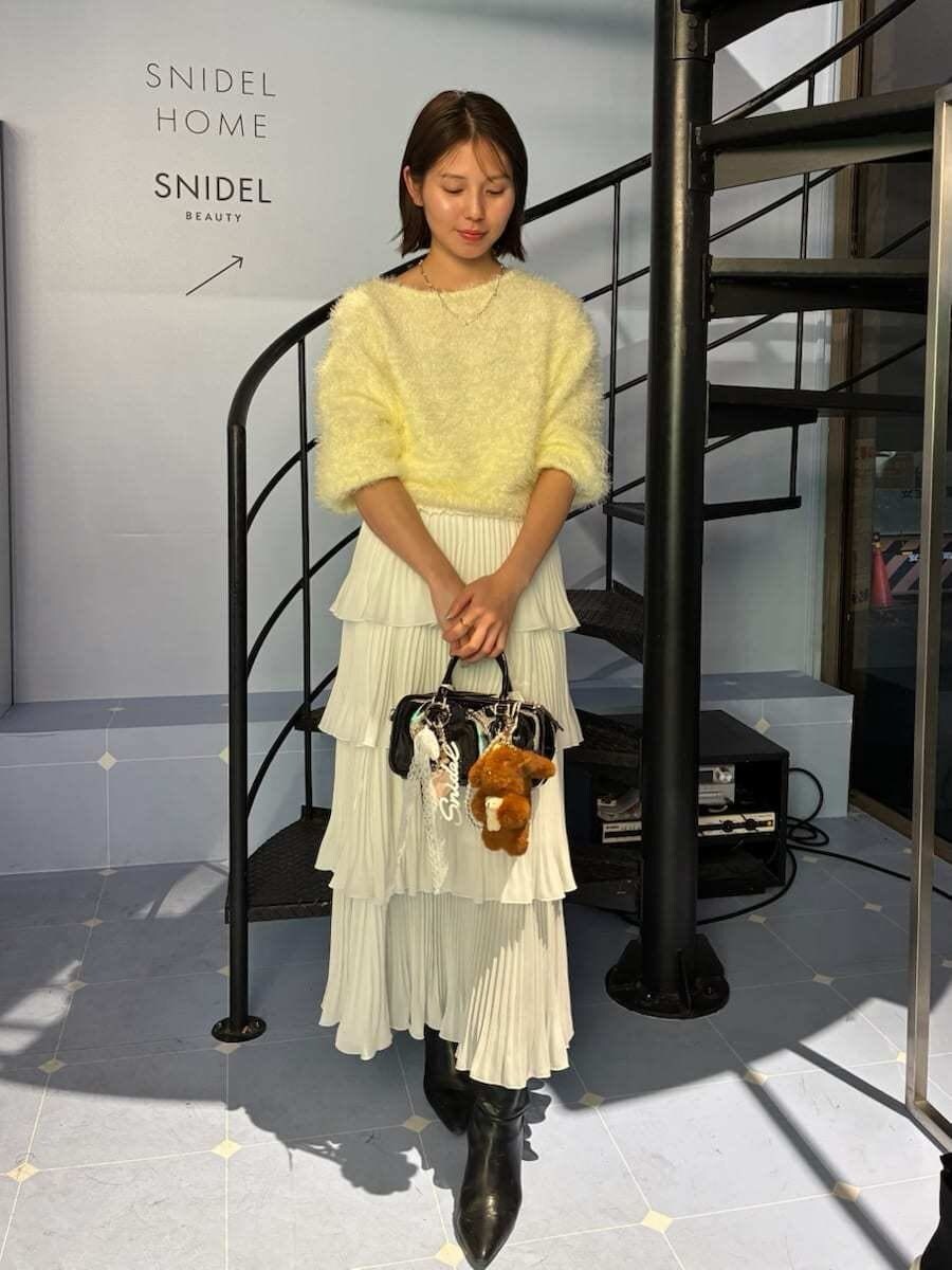 ブラック系のブーツ、ブラック系のボストンバッグ、イエロー系のニット/セーターを着用したレディースの冬コーディネートの2枚目の写真