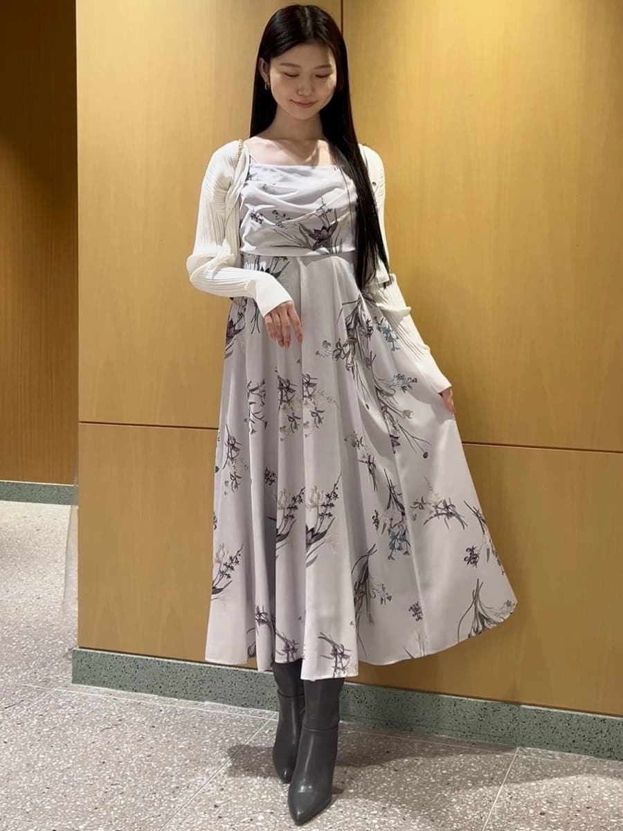 グレー系のブーツ、ホワイト系のカーディガン/ボレロ、パープル系のワンピースを着用したレディースの冬コーディネートの2枚目の写真