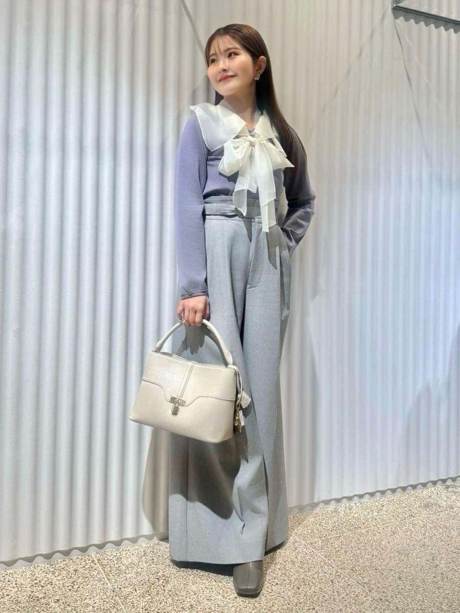 ブラック系のチェスターコート、ブルー系のニット/セーター、ホワイト系のハンドバッグを着用したレディースの冬コーディネートの7枚目の写真