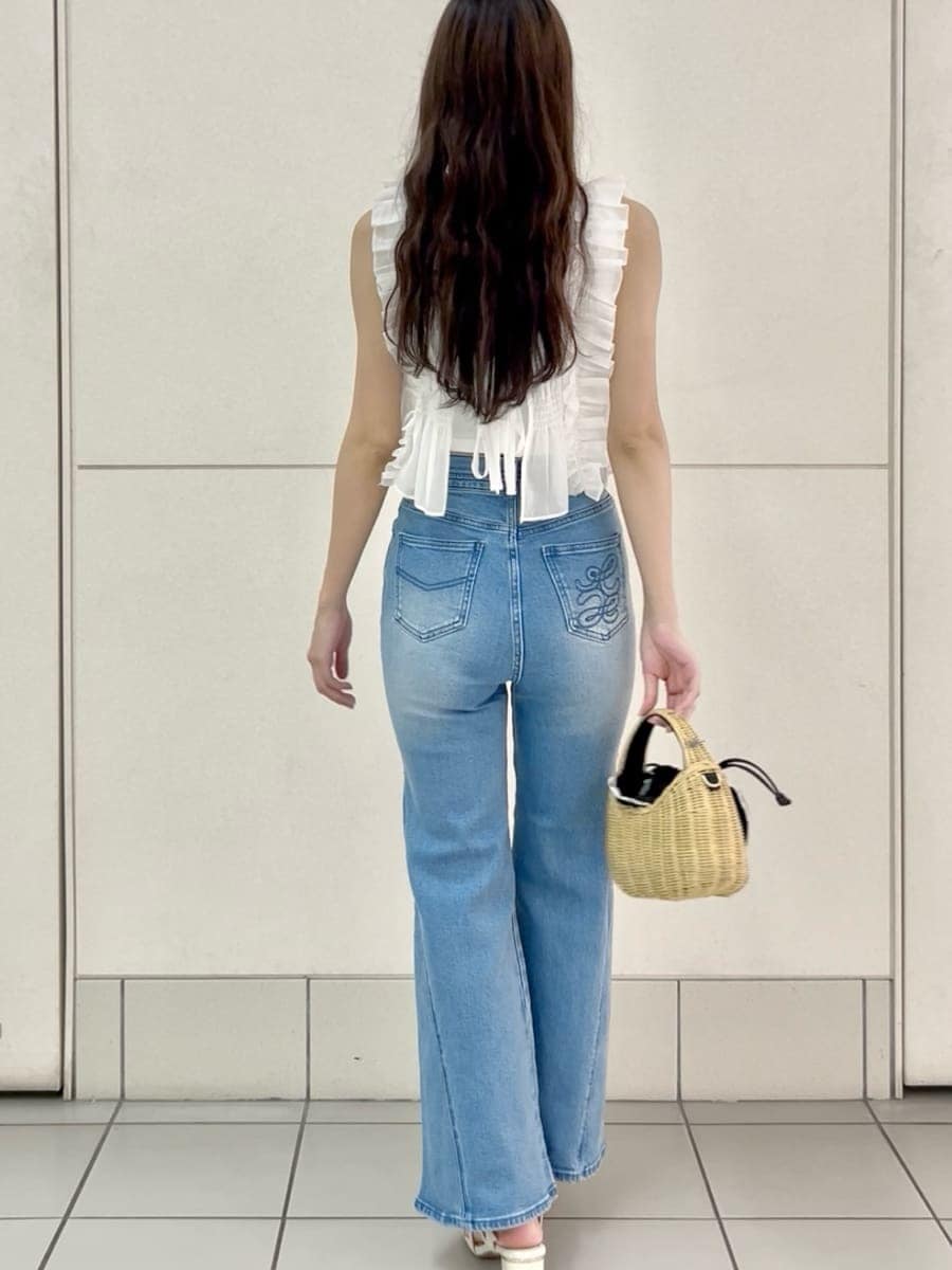 ブルー系のデニムパンツ、ブラック系のかごバッグ、ホワイト系のシャツ/ブラウスを着用したレディースの夏コーディネートの4枚目の写真