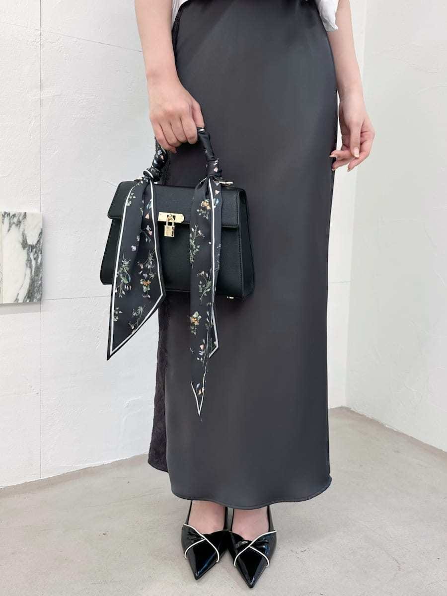ブラック系のパンプス、ブラック系のハンドバッグ、グレー系のスカートを着用したレディースの夏コーディネートの4枚目の写真