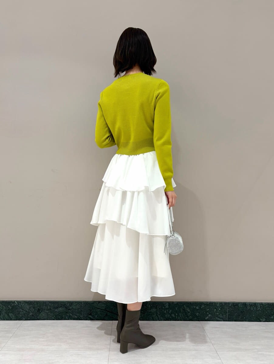 イエロー系のワンピース、ゴールド系のイヤリングを着用したレディースの冬コーディネートの3枚目の写真