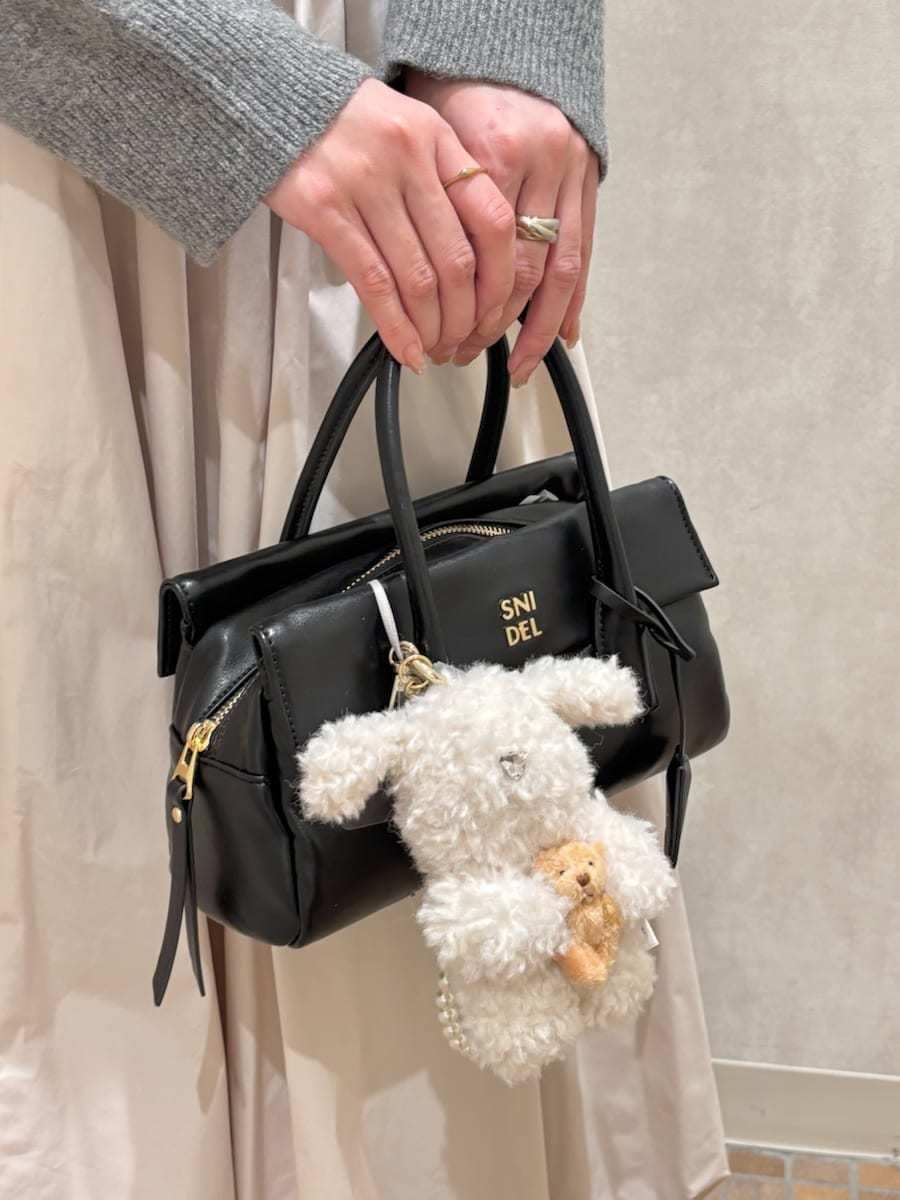 ベージュ系のスカート、ブラック系のボストンバッグ、ホワイト系のキーケース/キーアクセサリーを着用したレディースの秋コーディネートの6枚目の写真