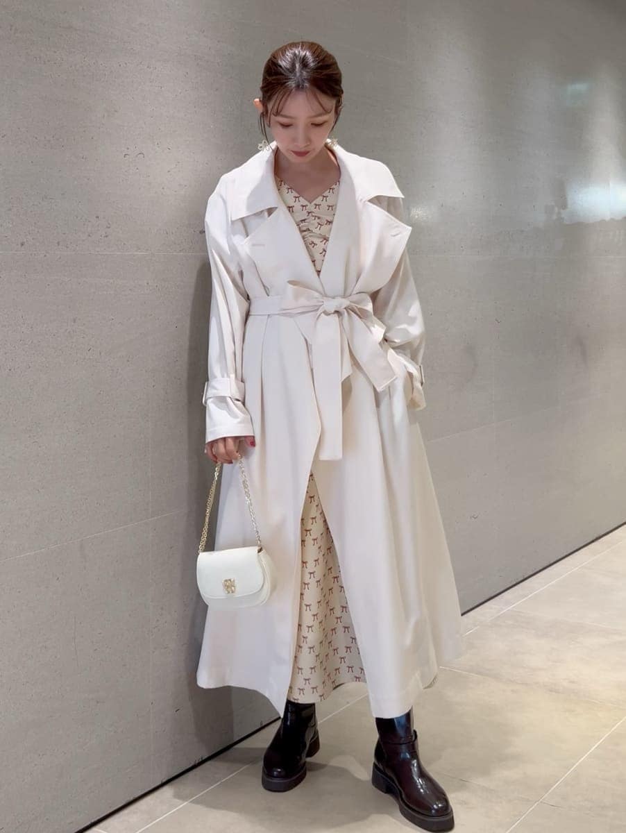 ホワイト系のトレンチコート、ベージュ系のワンピース、ホワイト系のショルダーバッグを着用したレディースの冬コーディネートの4枚目の写真