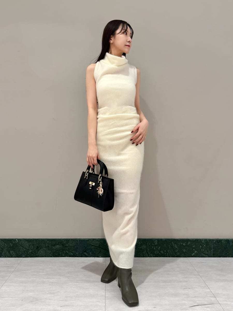 ホワイト系のワンピース、ブラック系のハンドバッグ、ブラウン系のチェスターコートを着用したレディースの冬コーディネートの5枚目の写真