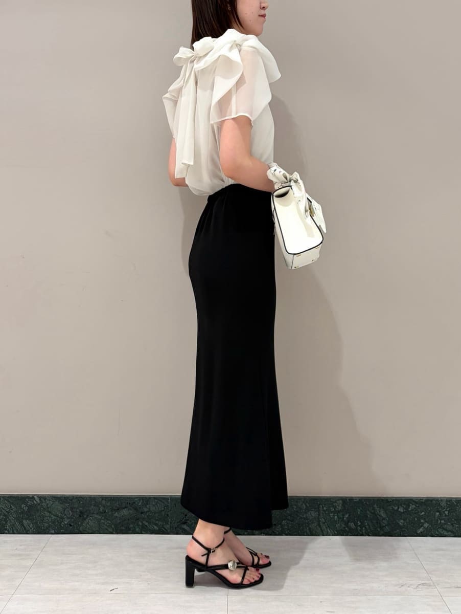 ブラック系のスカート、ホワイト系のシャツ/ブラウス、ホワイト系のハンドバッグを着用したレディースの春コーディネートの2枚目の写真