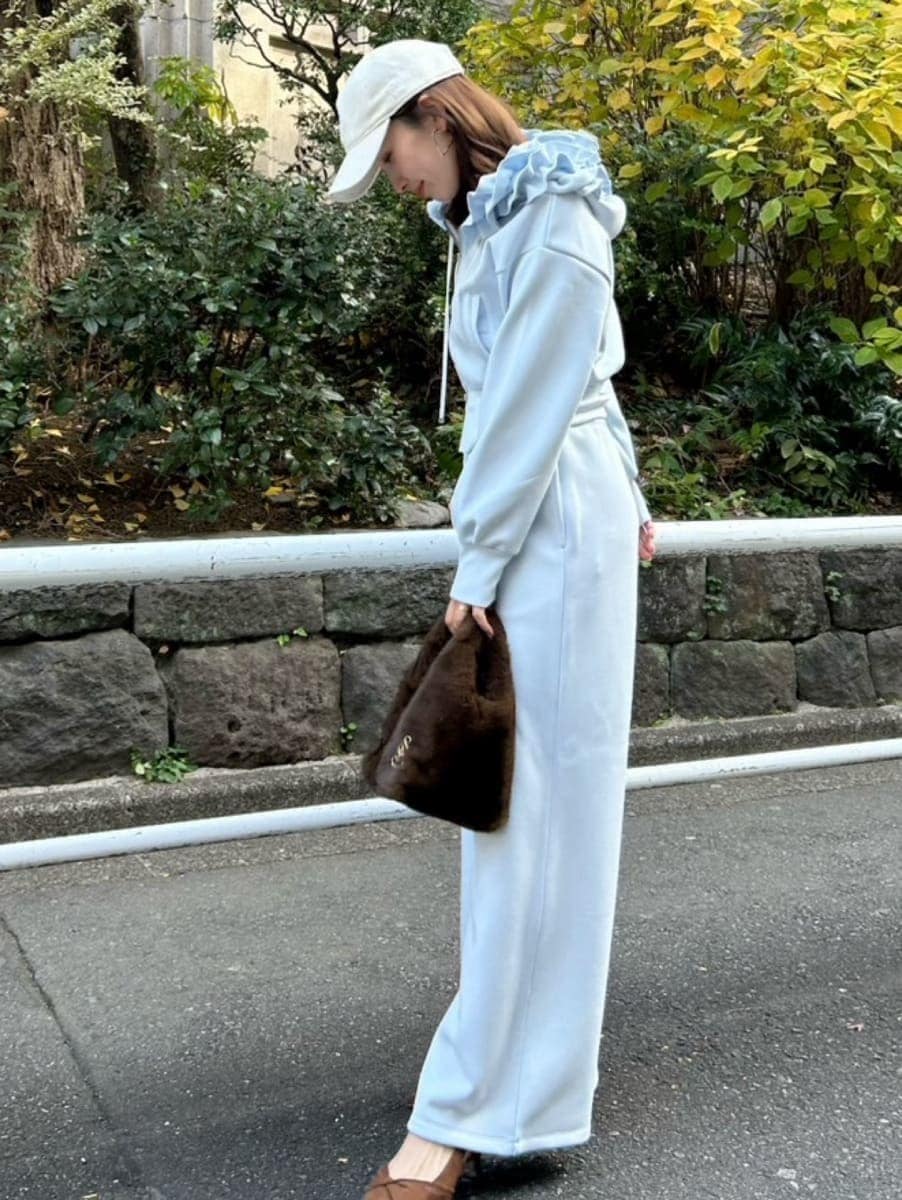 ブラウン系のハンドバッグ、ブルー系のパーカー、ブルー系のスウェットパンツを着用したレディースの冬コーディネートの3枚目の写真