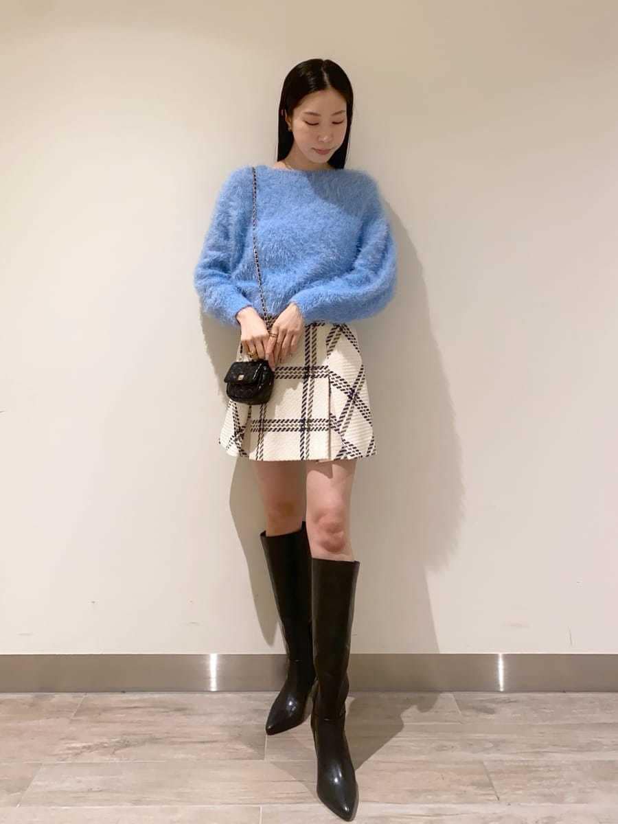 ホワイト系のスカート、ブラック系のブーツ、ブラック系のショルダーバッグを着用したレディースの冬コーディネートの5枚目の写真