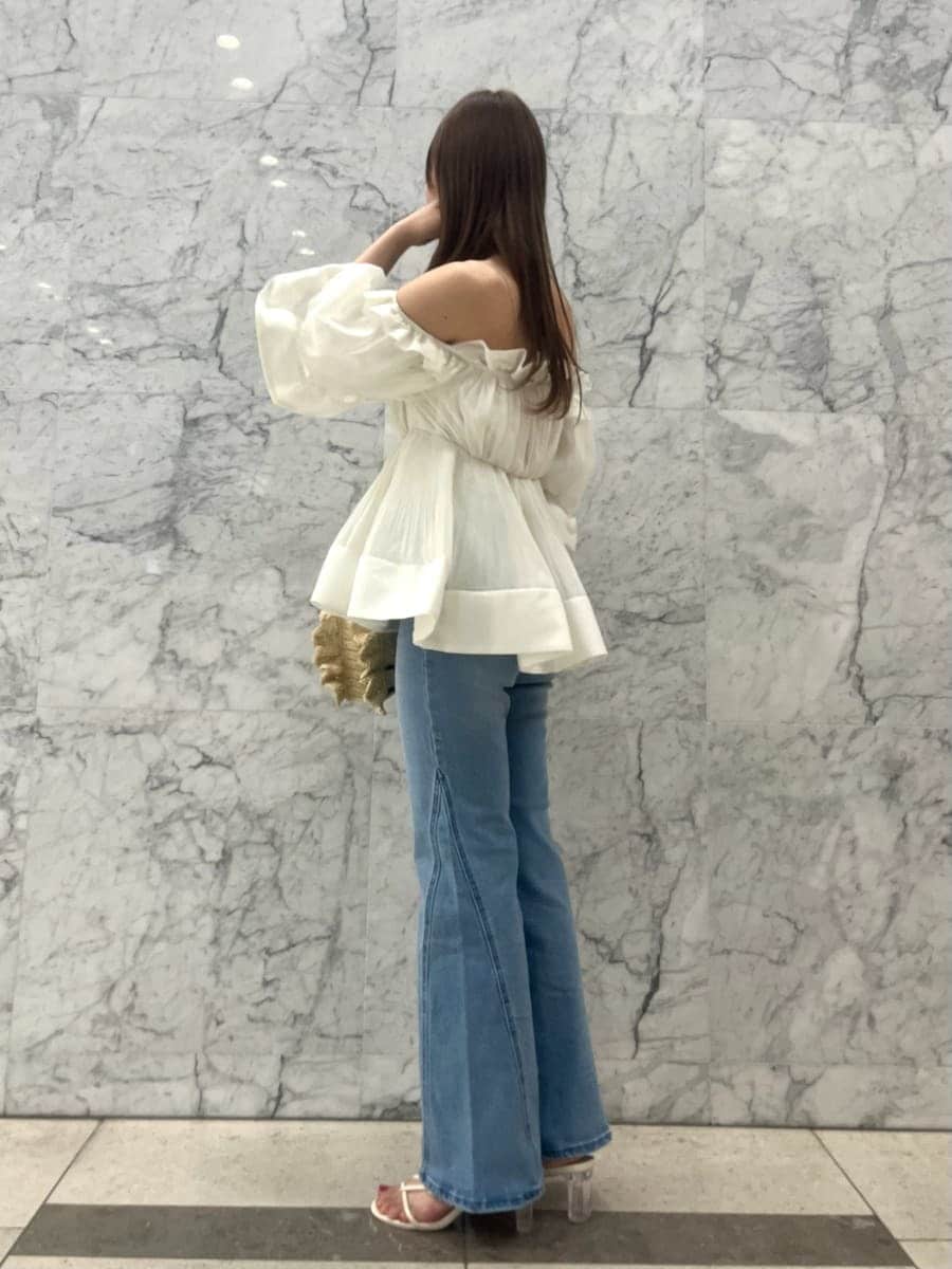 ブルー系のデニムパンツ、ホワイト系のその他トップス、ベージュ系のショルダーバッグを着用したレディースの春コーディネートの3枚目の写真