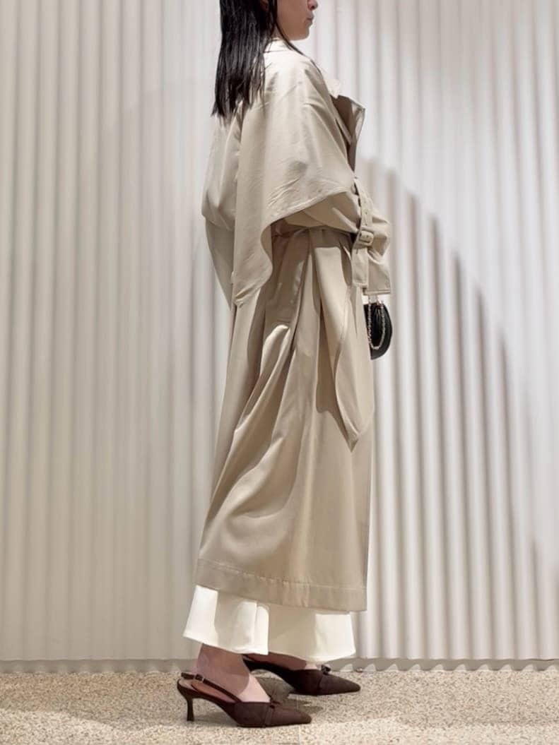 ベージュ系のトレンチコート、ホワイト系のスカート、ブラウン系のパンプスを着用したレディースの冬コーディネートの2枚目の写真