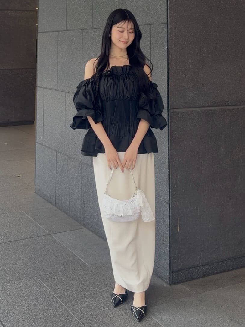 ホワイト系のスカート、ブラック系のその他トップス、ブラック系のパンプスを着用したレディースの春コーディネートの2枚目の写真