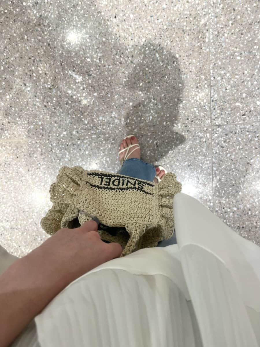 ブルー系のデニムパンツ、ホワイト系のその他トップス、ベージュ系のショルダーバッグを着用したレディースの春コーディネートの6枚目の写真
