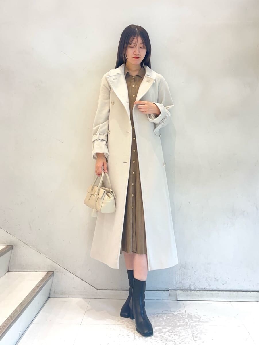 ホワイト系のチェスターコート、ベージュ系のワンピース、ホワイト系のボストンバッグを着用したレディースの秋コーディネートの2枚目の写真