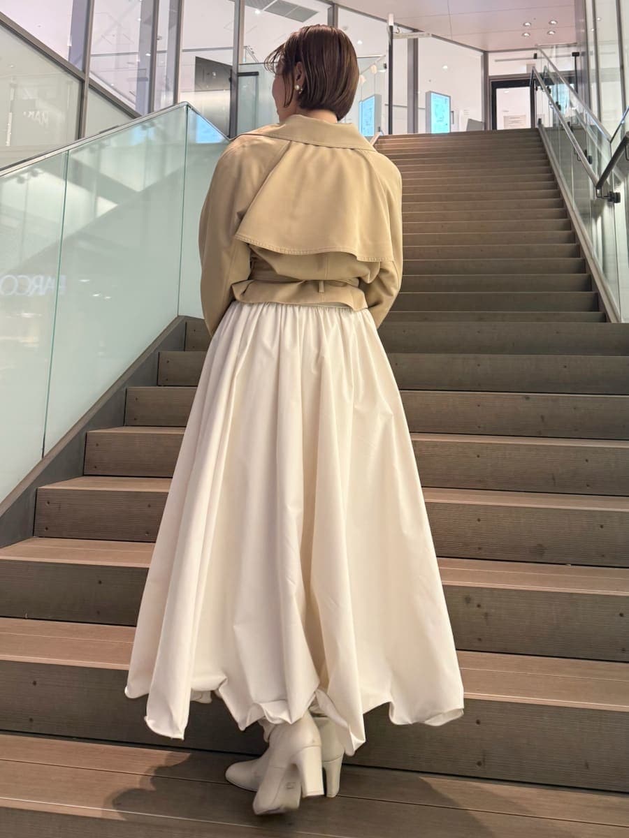 ベージュ系のトレンチコート、ホワイト系のスカート、その他のニット/セーターを着用したレディースの冬コーディネートの9枚目の写真