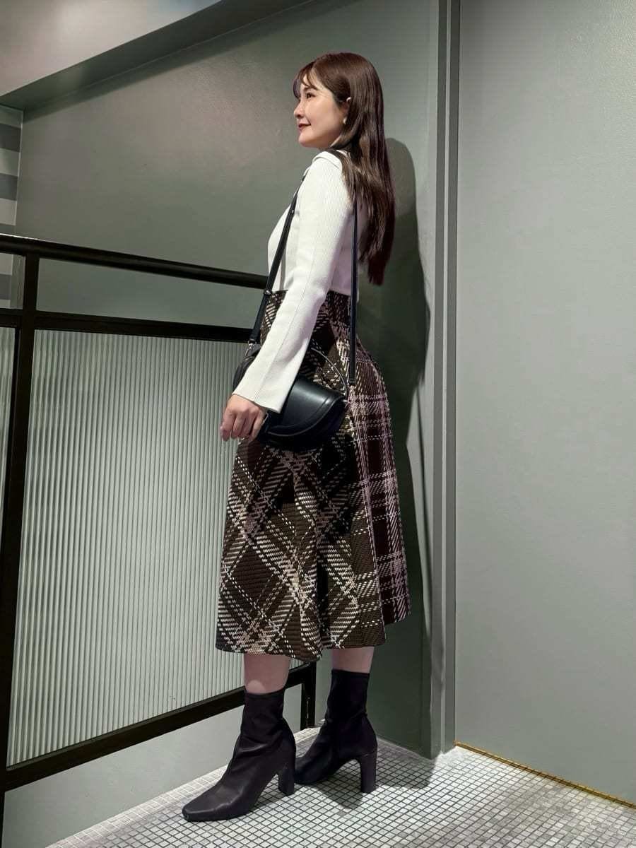 ホワイト系のニット/セーター、ブラウン系のスカート、レッド系のブーツを着用したレディースの秋コーディネートの2枚目の写真