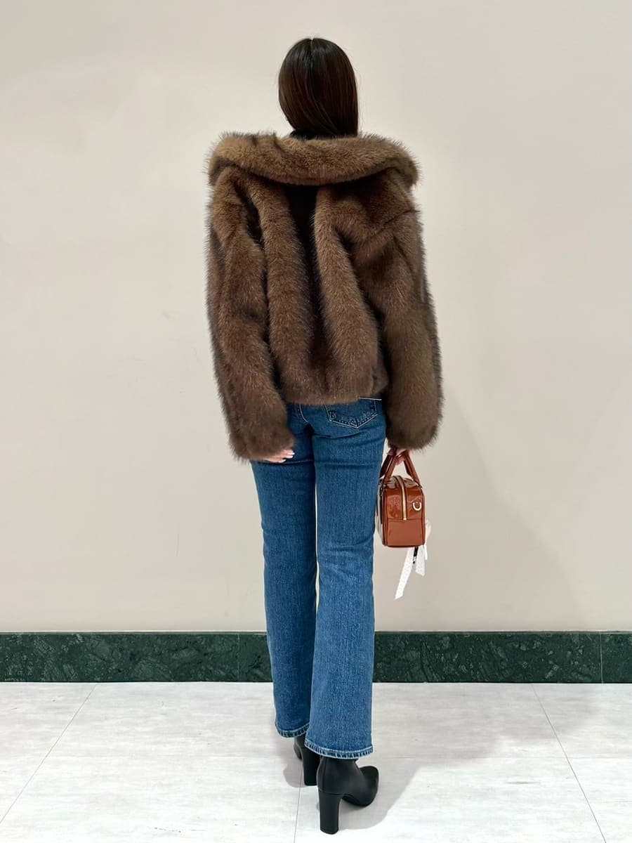 ブラウン系のチェスターコート、ブラック系のニット/セーター、ブルー系のデニムパンツを着用したレディースの秋コーディネートの3枚目の写真