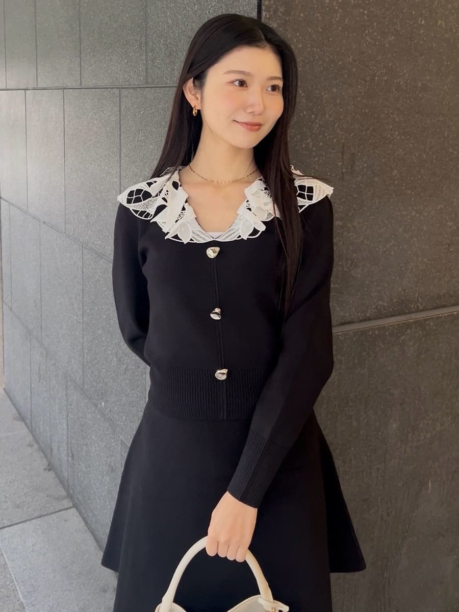 ブラック系のブーツ、ブラック系のワンピース、ホワイト系のハンドバッグを着用したレディースの冬コーディネートの4枚目の写真