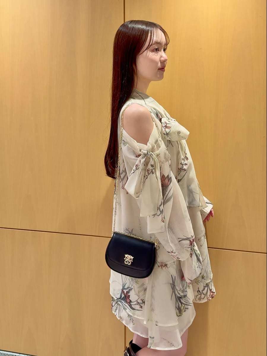 イエロー系のワンピース、ブラック系のショルダーバッグ、シルバー系のピアス（両耳用）を着用したレディースの冬コーディネートの6枚目の写真