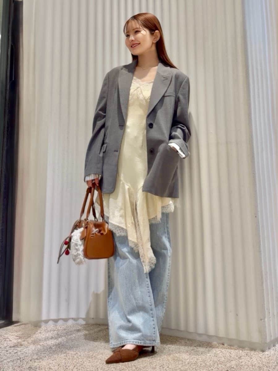 グレー系のテーラードジャケット、ブルー系のデニムパンツ、イエロー系のキャミソールを着用したレディースの春コーディネートの2枚目の写真