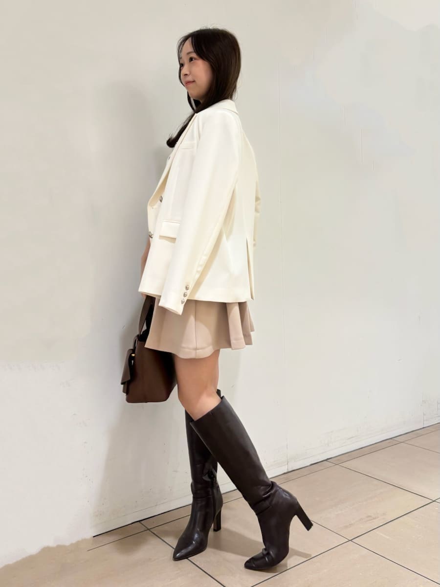 ブラウン系のブーツ、ホワイト系のテーラードジャケット、ベージュ系のスカートを着用したレディースの冬コーディネートの2枚目の写真