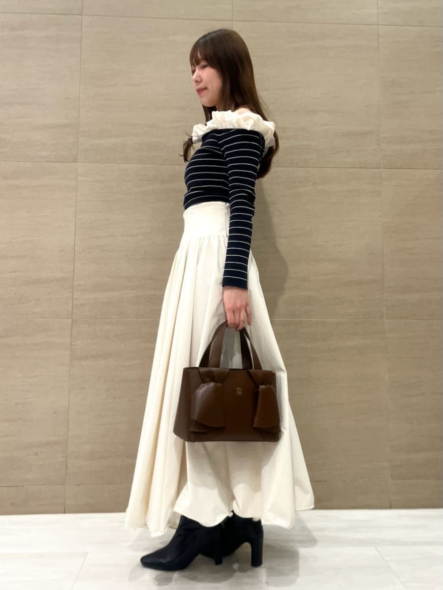 ブラック系のブーツ、ホワイト系のスカート、その他のニット/セーターを着用したレディースの冬コーディネートの2枚目の写真