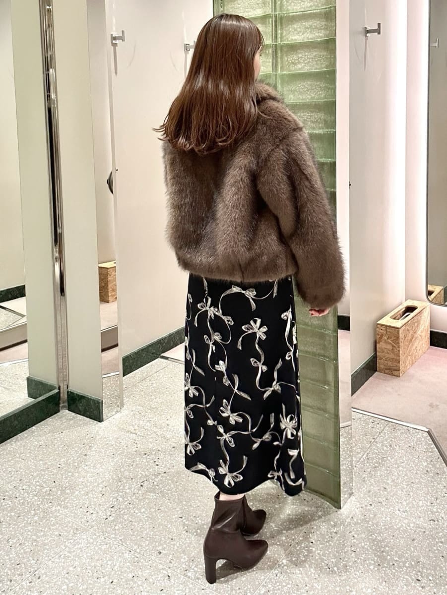 ブラウン系のチェスターコート、ブルー系のワンピース、レッド系のブーツを着用したレディースの秋コーディネートの5枚目の写真