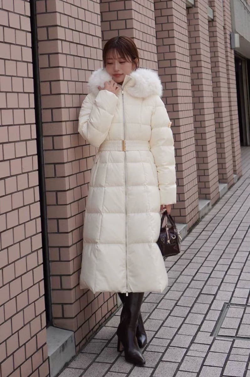 ブラック系のブーツ、ブラック系のボストンバッグ、ホワイト系のダウンジャケット/コートを着用したレディースの秋コーディネートの2枚目の写真