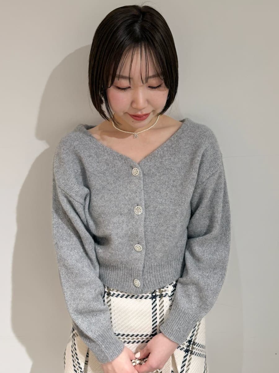 ホワイト系のスカート、グレー系のカーディガン/ボレロ、ゴールド系のキーケース/キーアクセサリーを着用したレディースの冬コーディネートの3枚目の写真