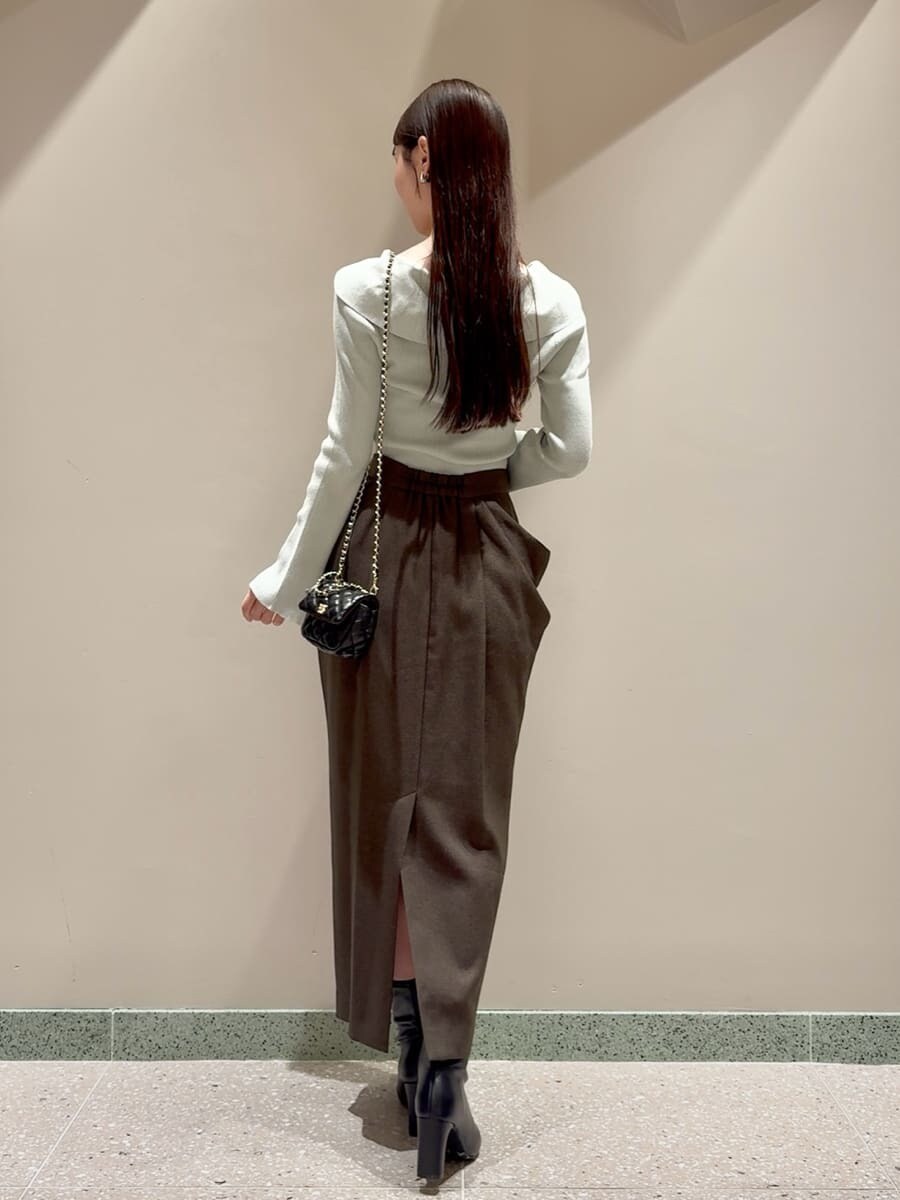 グリーン系のニット/セーター、ブラウン系のスカート、ブラック系のブーツを着用したレディースの秋コーディネートの3枚目の写真