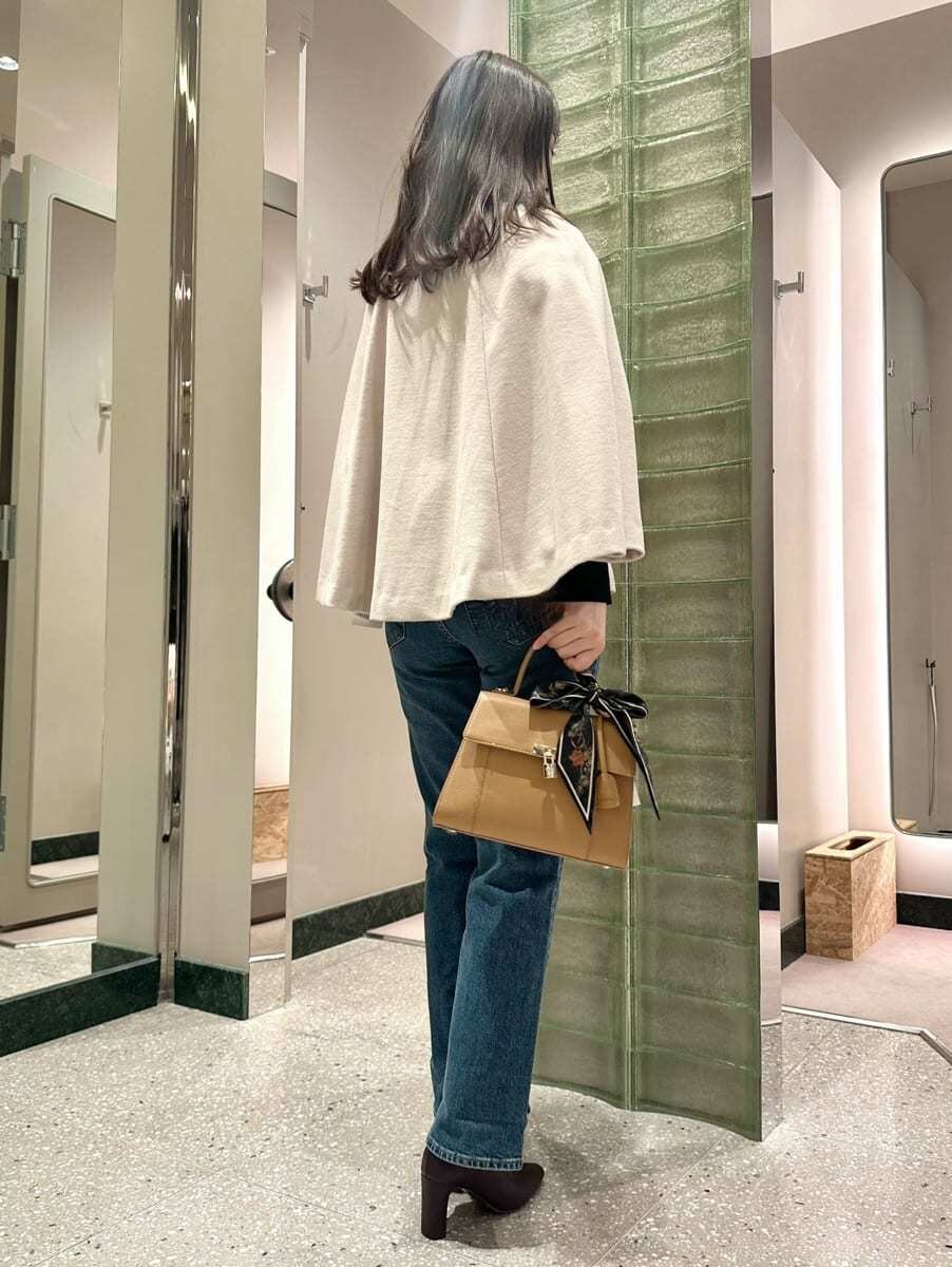 ホワイト系のチェスターコート、ブルー系のデニムパンツを着用したレディースの秋コーディネートの5枚目の写真