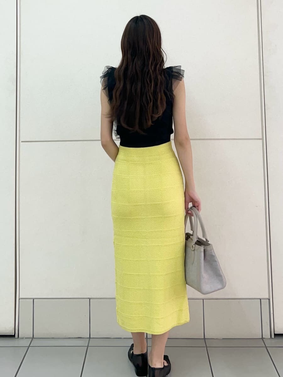 ブラック系のニット/セーター、イエロー系のスカート、ピンク系のハンドバッグを着用したレディースの夏コーディネートの4枚目の写真