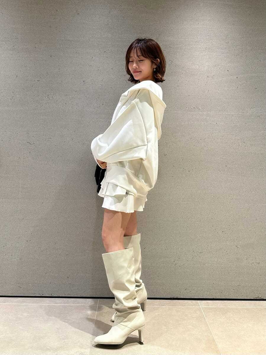 ホワイト系のパーカー、ホワイト系のブーツ、ブラック系のショルダーバッグを着用したレディースの冬コーディネートの4枚目の写真