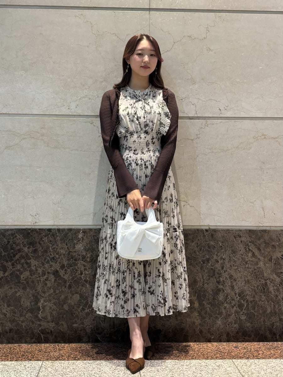 ベージュ系のワンピース、ホワイト系のカーディガン/ボレロ、ブラウン系のパンプスを着用したレディースの冬コーディネートの2枚目の写真