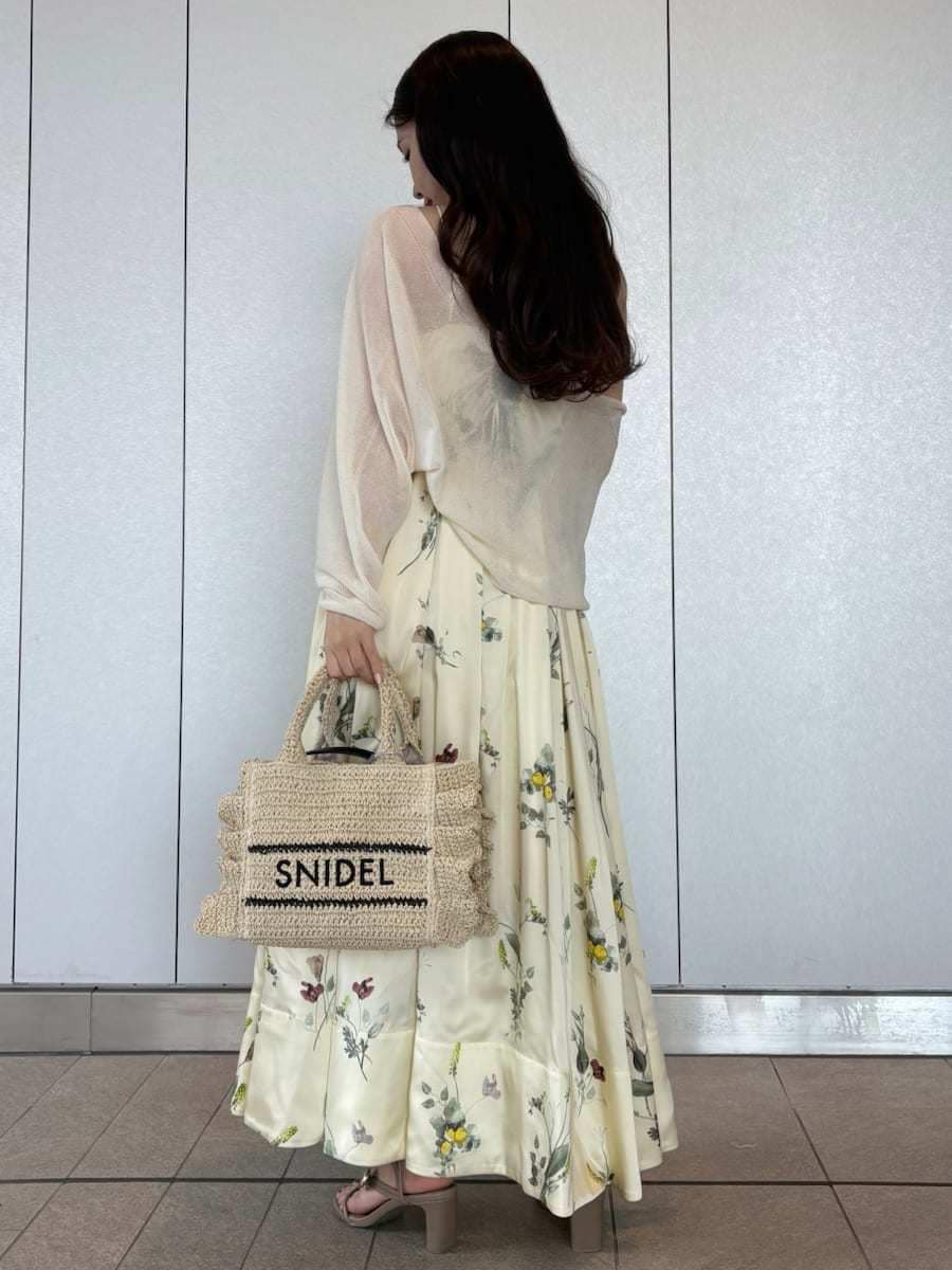 イエロー系のワンピース、ホワイト系のカーディガン/ボレロ、ベージュ系のショルダーバッグを着用したレディースの春コーディネートの3枚目の写真