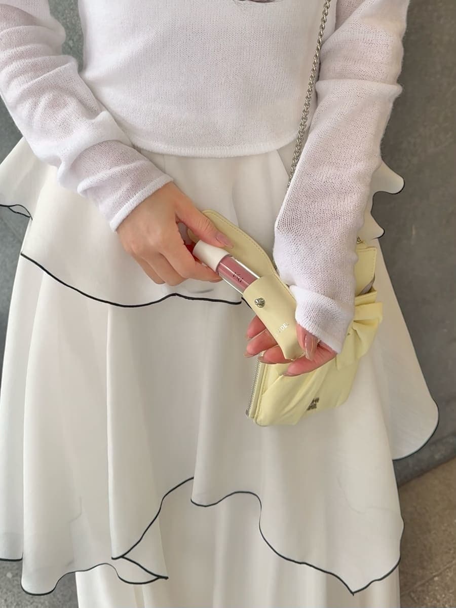 ホワイト系のワンピース、ブラック系のパンプス、イエロー系のショルダーバッグを着用したレディースの冬コーディネートの6枚目の写真