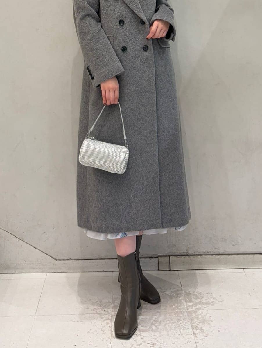 グレー系のワンピース、グレー系のチェスターコート、ゴールド系のイヤリングを着用したレディースの冬コーディネートの8枚目の写真
