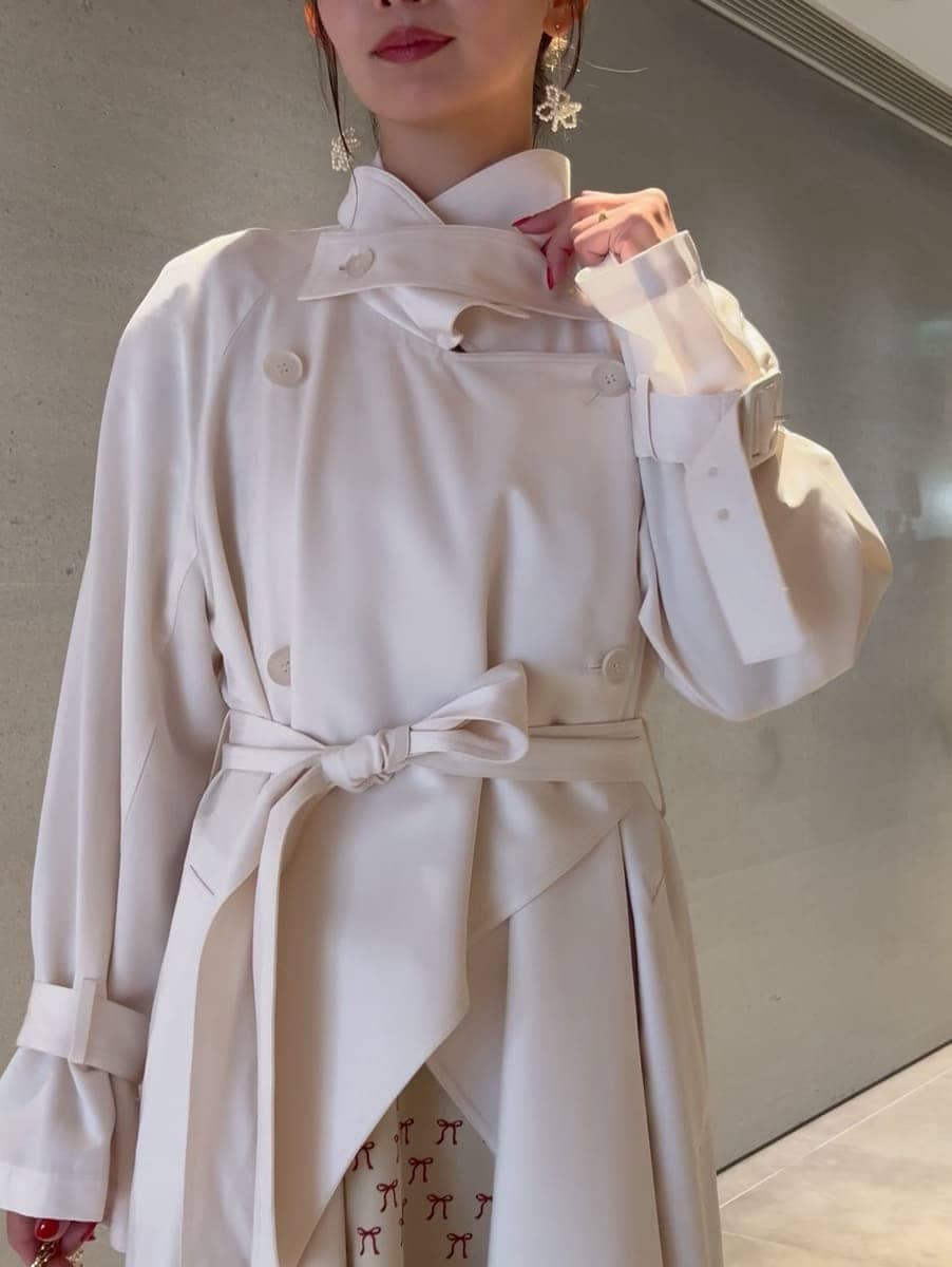 ホワイト系のトレンチコート、ベージュ系のワンピース、ホワイト系のショルダーバッグを着用したレディースの冬コーディネートの3枚目の写真