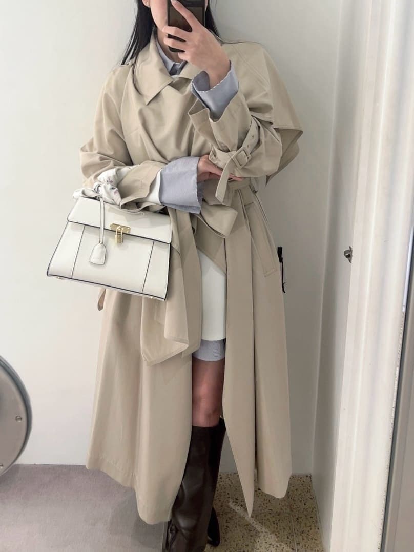 ブラウン系のブーツ、ベージュ系のトレンチコート、ホワイト系のハンドバッグを着用したレディースの冬コーディネートの10枚目の写真