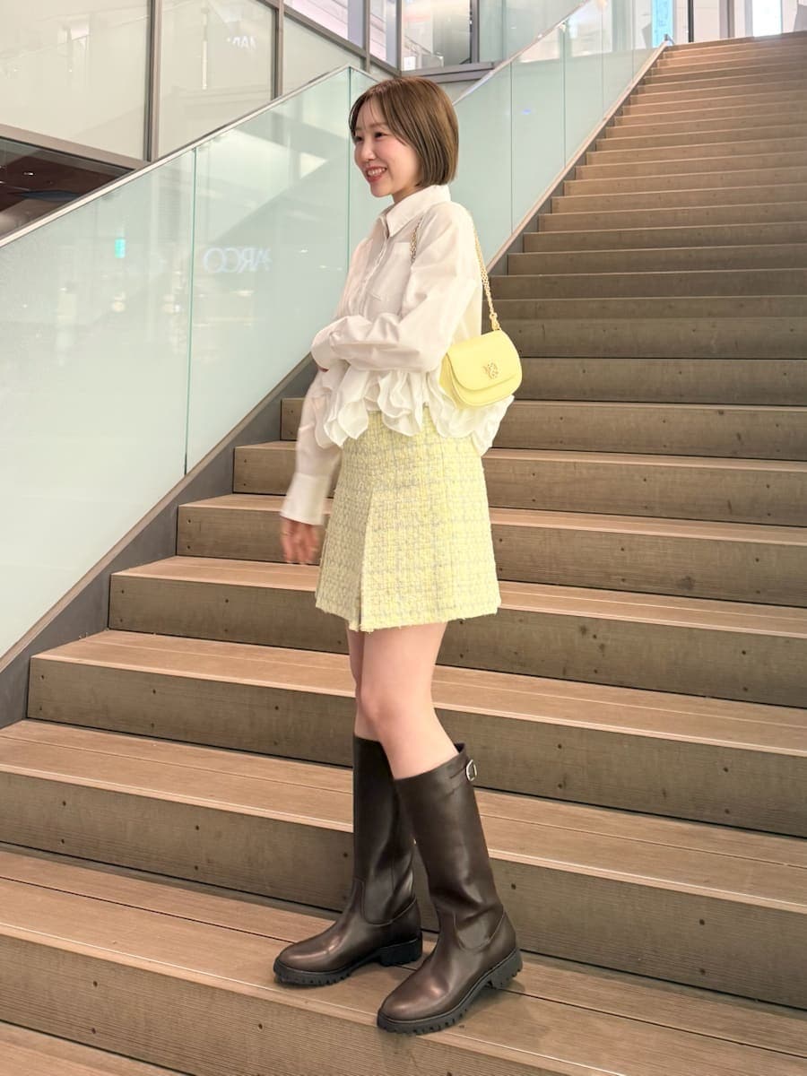イエロー系のスカート、ホワイト系のシャツ/ブラウス、イエロー系のショルダーバッグを着用したレディースの冬コーディネートの2枚目の写真