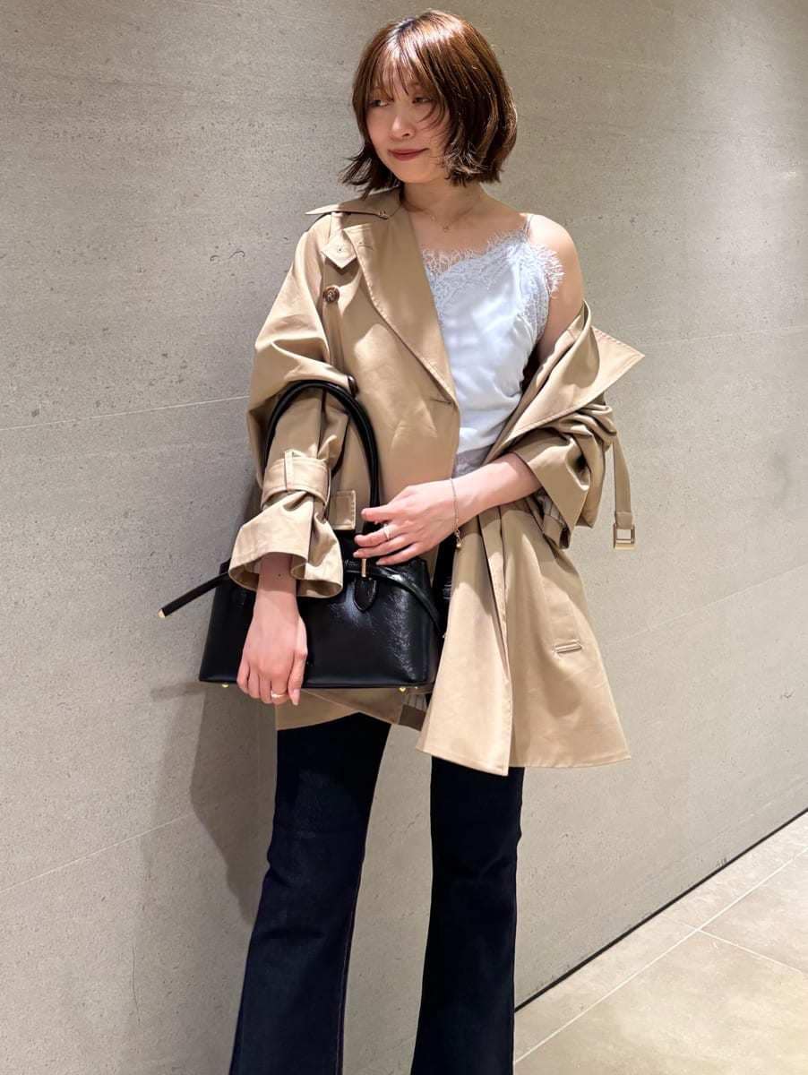 ブルー系のデニムパンツ、ベージュ系のトレンチコート、ブルー系のキャミソールを着用したレディースの秋コーディネートの6枚目の写真