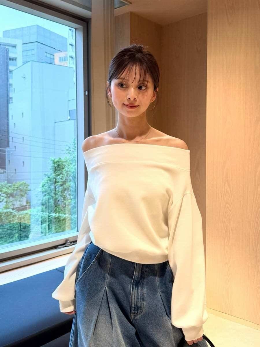 ブルー系のデニムパンツ、ホワイト系のワンピース、ブラック系のボストンバッグを着用したレディースの秋コーディネートの3枚目の写真